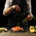 The chef prepares fresh salmon fish, freshly salted trout, sprinkled with rosemary leaves with ingredients. Salmon steak,