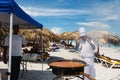 Chef prepares a giant seafood paella on beach Varadero near sunbathing tourists