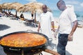 Chef prepares a giant seafood paella on beach Varadero near sunbathing tourists