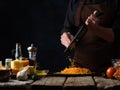 The chef prepares the ingredients for making Italian pasta. Grips cheese. Nearby, on a wooden table, cheese, garlic, tomatoes, Royalty Free Stock Photo