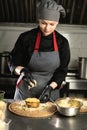 the chef prepares liver pie in the kitchen. Portrait of a woman chef in special clothes puts cheese on liver pancakes. Royalty Free Stock Photo