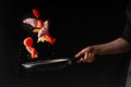 Chef prepares meat with vegetables, on a black background, roasting, tasty food, recipe book, menu, restaurant business