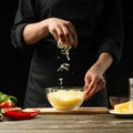 The chef prepares mozzarella cheese, cheddar for Italian pizza, pasta. On a black background, freezing in motion. A concept of