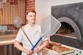 The chef prepares pizza in a neapolitan pizzeria. Cook in a apron in the kitchen with a shovel in his hands. boxes for Royalty Free Stock Photo