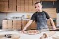 The chef prepares pizza. Raw pizza ready to bake. Cook in a blue apron in the kitchen. with a shovel in his hands. boxes Royalty Free Stock Photo