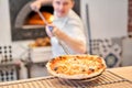 The chef prepares pizza. Raw pizza ready to bake. Cook in a blue apron in the kitchen. with a shovel in his hands. boxes Royalty Free Stock Photo