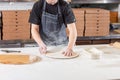 The chef prepares pizza. Raw pizza ready to bake. Cook in a blue apron in the kitchen. with a shovel in his hands. boxes Royalty Free Stock Photo