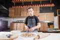 The chef prepares pizza. Raw pizza ready to bake. Cook in a blue apron in the kitchen. with a shovel in his hands. boxes Royalty Free Stock Photo