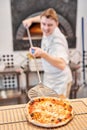 The chef prepares pizza. Raw pizza ready to bake. Cook in a blue apron in the kitchen. with a shovel in his hands. boxes Royalty Free Stock Photo