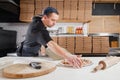 The chef prepares pizza. Raw pizza ready to bake. Cook in a blue apron in the kitchen. with a shovel in his hands. boxes Royalty Free Stock Photo