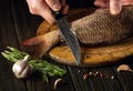 The chef prepares raw fresh fish with spices. Preparation for cutting fish with a knife. Working environment on the kitchen table Royalty Free Stock Photo