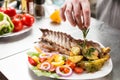 Decorated with a sprig of rosemary. the chef prepares in the restaurant. Grilled rack of lamb with fried potatoes and Royalty Free Stock Photo