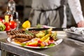 The chef prepares in the restaurant. Grilled rack of lamb with fried potatoes and fresh vegetables Royalty Free Stock Photo