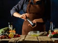 The chef prepares the sauce for the Greek salad. He adds spices to olive oil. Many ingredients for the salad lie next to each Royalty Free Stock Photo