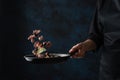 Chef prepares seafood with slice of lime in frying a pan, on a black background for design, recipe book, menu, restaurant or hotel