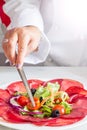 Chef preparing dish with bersaola and mixed salad Royalty Free Stock Photo
