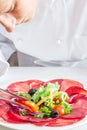 Chef preparing dish with bersaola and mixed salad Royalty Free Stock Photo