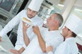 Chef preparing food in kitchen with apprentices Royalty Free Stock Photo