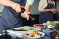 Chef preparing fried meat with salad for serving in restaurant kitchen Royalty Free Stock Photo