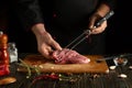 A chef is preparing a meat steak with aromatic spices on the kitchen table in a restaurant. The concept of cooking barbecue from Royalty Free Stock Photo