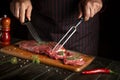 The chef preparing raw fresh beef meat on cutting board before baking or barbecue. Recipe idea for a restaurant or hotel Royalty Free Stock Photo