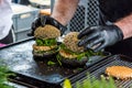 Chef preparing tasty burgers at outdoor stand.