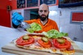 Chef preparing tasty sub sandwich from fresh ingredients. Royalty Free Stock Photo