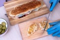 Chef preparing tasty sub sandwich from fresh ingredients. Royalty Free Stock Photo