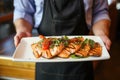 chef presenting a plate of grilled salmon steaks to customers Royalty Free Stock Photo