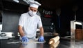 Chef  with protective coronavirus face mask preparing pizza Royalty Free Stock Photo