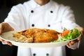 Chef proudly presenting Fried sea bass fish on white plate