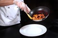 The chef puts the flambe berries and fruit on a plate. Unrecognizable photo. Flaming of fruits and berries on fire.Top view Royalty Free Stock Photo