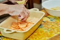 Chef puts potatoes and sweet potatoes in ceramic baking dish. Potato and sweet potato gratin with Provence herbs. French Royalty Free Stock Photo