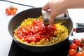 The Chef Puts the Tomatoes in their own juice into a Pan with Chopped Bell Peppers and Onions, which are fried on the Stove.