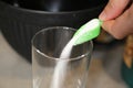 Pouring sugar grains into a clear glass.