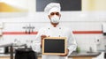 Chef in respirator with chalkboard at kitchen