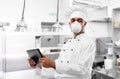 Chef in respirator with tablet pc at kitchen Royalty Free Stock Photo