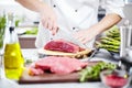 Chef in restaurant kitchen cooking,he is cutting meat or steak Royalty Free Stock Photo