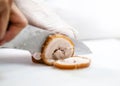 Chef in restaurant kitchen cutting meat, chef hands slicing belly pork rolled joint