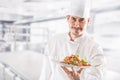 Chef in restaurant kitchen holding plate with italian meal spagh Royalty Free Stock Photo