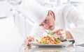 Chef in restaurant kitchen prepares and decorates meal with hands.Cook preparing spaghetti bolognese Royalty Free Stock Photo