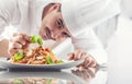 Chef in restaurant kitchen prepares and decorates meal with hands.Cook preparing spaghetti bolognese Royalty Free Stock Photo