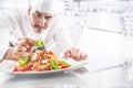Chef in restaurant kitchen prepares and decorates meal with hands.Cook preparing spaghetti bolognese Royalty Free Stock Photo