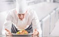 Chef in restaurant kitchen prepares and decorates meal with hands.Cook preparing spaghetti bolognese Royalty Free Stock Photo