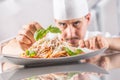 Chef in restaurant kitchen prepares and decorates meal with hands.Cook preparing spaghetti bolognese Royalty Free Stock Photo