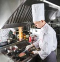 Chef in restaurant kitchen at stove with pan, cooking. Royalty Free Stock Photo