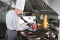 Chef in restaurant kitchen at stove with pan, cooking. Royalty Free Stock Photo