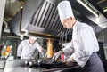 Chef in restaurant kitchen at stove with pan, cooking. Royalty Free Stock Photo