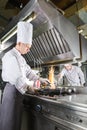 Chef in restaurant kitchen at stove with pan, cooking Royalty Free Stock Photo