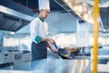 Chef in restaurant kitchen at stove and pan cooking flambe on food Royalty Free Stock Photo